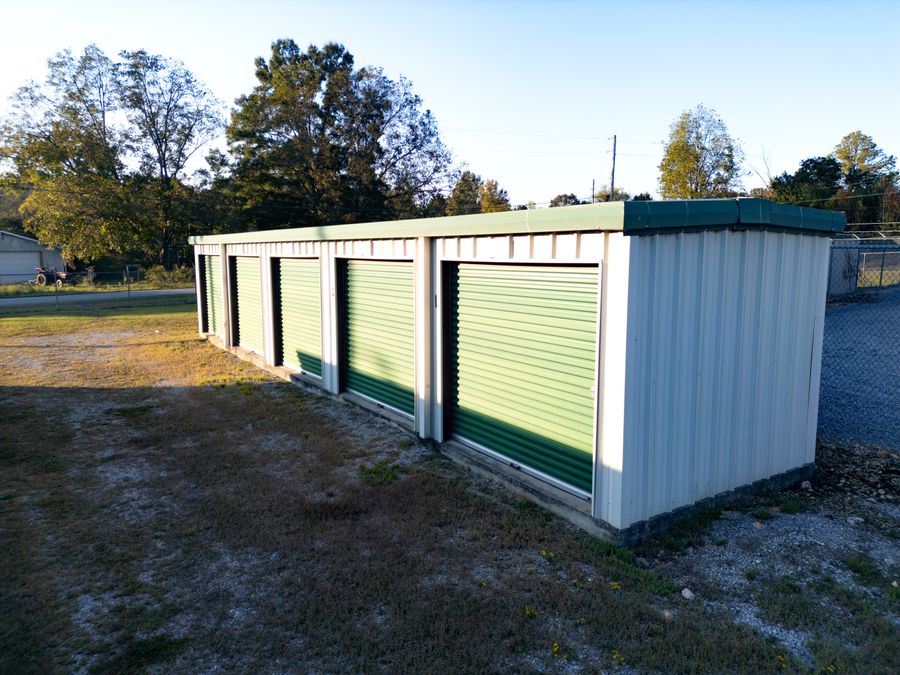 End of a Store Base building showing five green roll-up doors and white steel siding